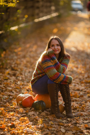 Smile woman sitting on the pumpkin on the autumanl maple leavesの写真素材