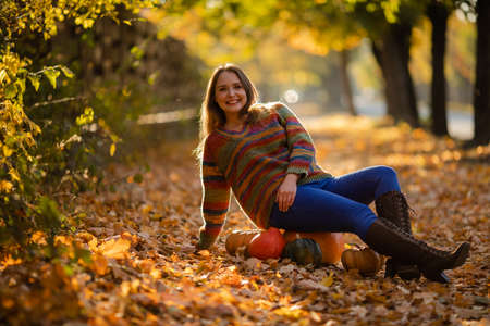 Smile woman sitting on the pumpkin on the autumanl maple leavesの写真素材