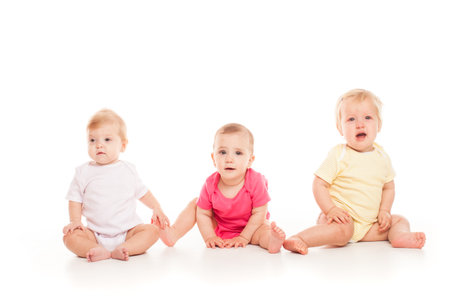 Three babies sitting isolated on a whiteの写真素材