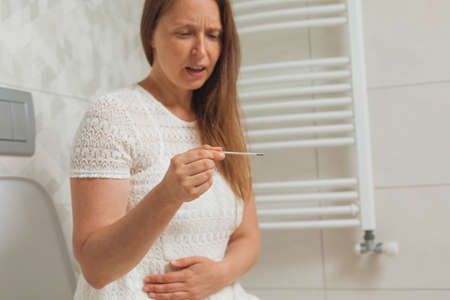 Worried middle age woman with pregnancy testの写真素材