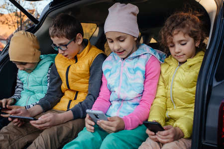 Children sitting on the car truck with smartphonesの写真素材