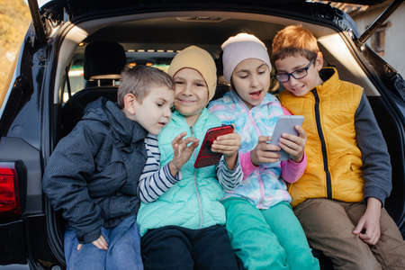Children sitting on the car truck with smartphonesの写真素材