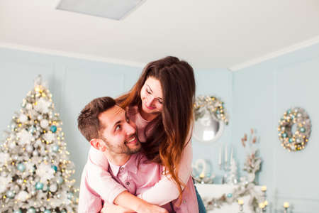 Young happy couple have fun and huggingnear christmas treeの写真素材