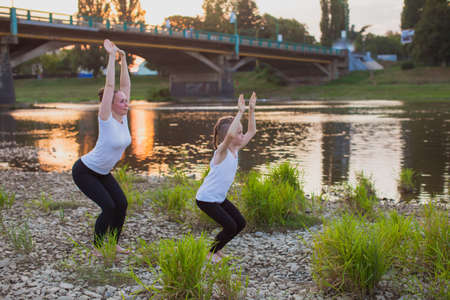 Mother and kid are doing exercises in the parkの写真素材