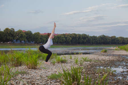 Young woman does yoga on rocks in nature