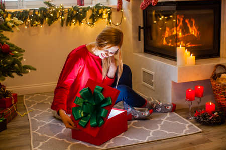 Woman open a red box gift near the fireplaceの写真素材