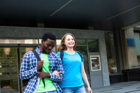 The young couple of diverse students leave the university buildingの写真素材