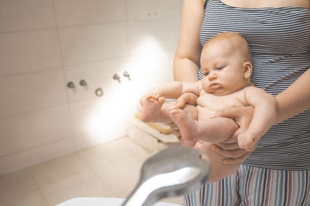 Mother washes her baby after stool at the showerの写真素材