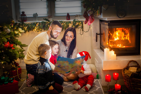 happy family father mother and children sitting by fireplace on Christmas Eveの写真素材
