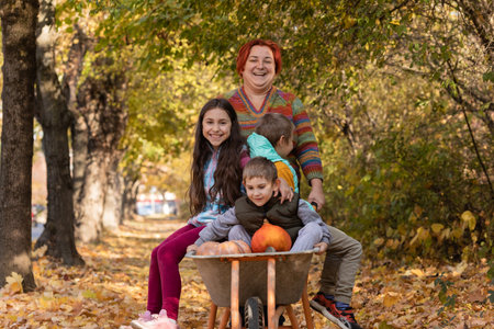 Mother have fun time with kids, use garden wheelbarrow with pumpkinsの写真素材