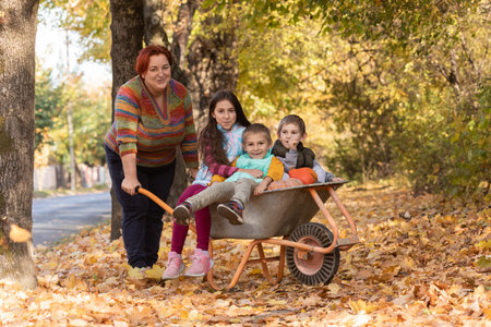 Mother have fun time with kids, use garden wheelbarrow with pumpkinsの写真素材
