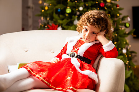 Adorable girl in Christmas dress near the classic decorated christmas treeの写真素材