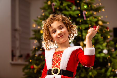 Adorable girl in Christmas dress near the classic decorated christmas treeの写真素材