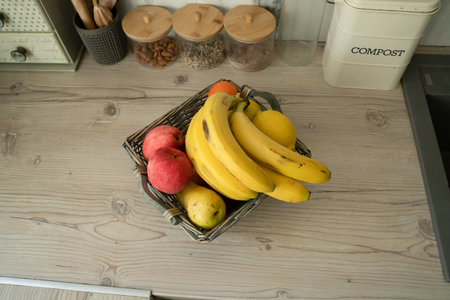 Basket with fresh fruits on table in kitchenの写真素材