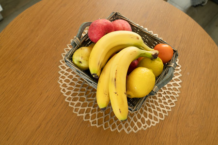 Basket with fresh fruits on table in kitchenの写真素材