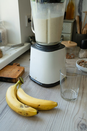 Vegan banana smoothie at the kitchen on the tableの写真素材