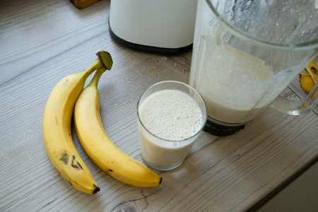 Vegan banana smoothie at the kitchen on the tableの写真素材