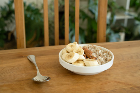 Oatmeal with banana, honey and almonda for breakfast on a tableの写真素材
