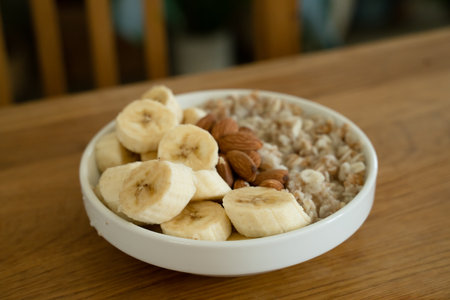 Oatmeal with banana, honey and almonda for breakfast on a tableの写真素材