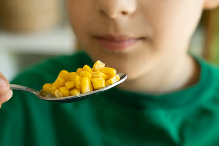 Boy eats marinated corn. Focus on the food and face on background