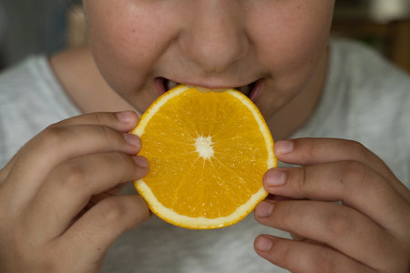 Teenage girl eats fruit. Focus on the food and face on backgroundの写真素材