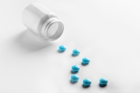 Medical blue pills and white bottle on white light background. Concept of healthcare and medicine.の写真素材