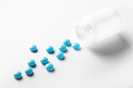 Medical blue pills and white bottle on white light background. Concept of healthcare and medicine.の写真素材