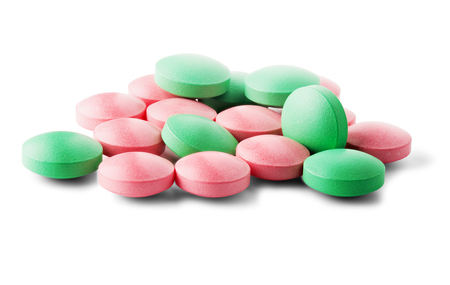 Heap of medical pills in green and pink colors on isolated white background. Concept of healthcare and medicine.の写真素材