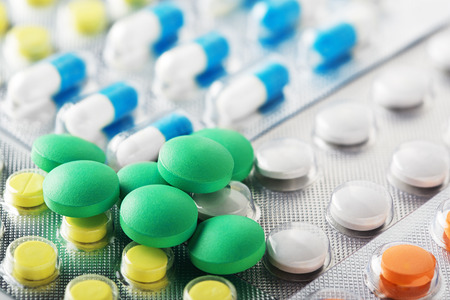 Heap of medical pills in white, blue and other colors. Pills in plastic package. Concept of healthcare and medicine.の写真素材