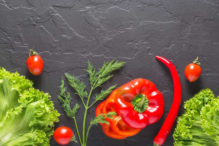 parsley, dill, cabbage leaves, pepper on a dark concrete background. Fresh products for salads and...