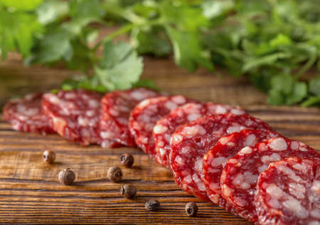 salami sausage with pepper and spices on a rustic wooden table, view from aboveの写真素材