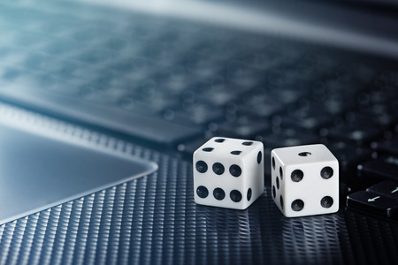 Dice on laptop computer keyboard. Ð¡oncept of online gambling and online casino. Creative idea with devil's bones and PC keyboard.の写真素材