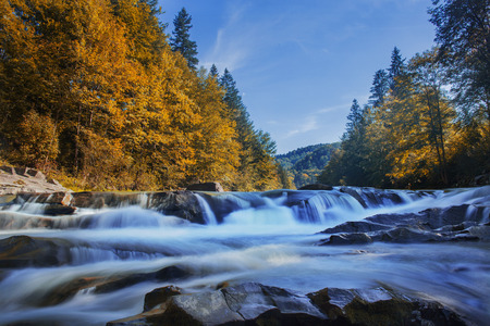 Long waterfall and river with rocks high in the mountains. Autumn mountains landscape. Idea for...
