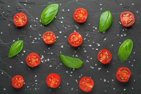 tomatoes basil and salt on a black backgroundの写真素材