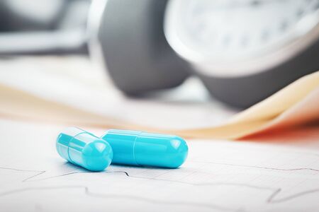 Medical pills on the background of ECG, cardiogram and cardiac gauge.  Diagnostics, prevention and...