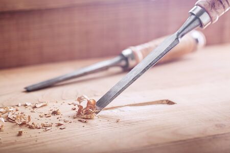 wood chisel shaving out groove in old pine plank for the door lock