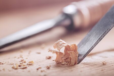 wood chisel shaving out groove in old pine plank for the door lock