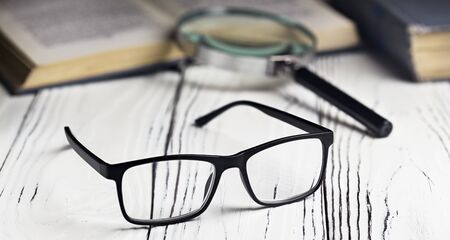 Glasses and a book on a wooden table. Vision problems.