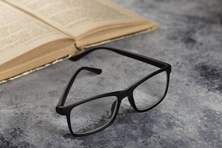 Glasses and a book on a table. Vision problems.