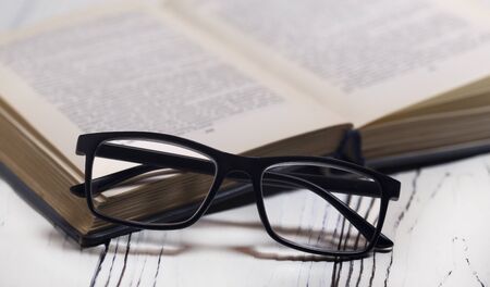 Glasses and a book on a wooden table. Vision problems.の写真素材
