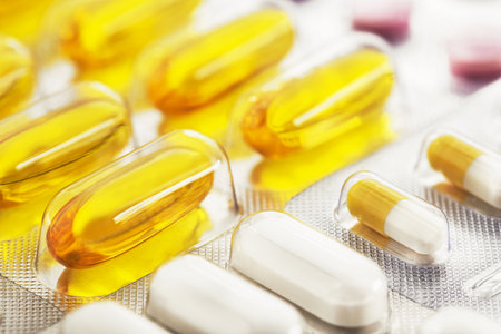 A bunch of medical pills in yellow and other colors. Tablets in plastic packaging.