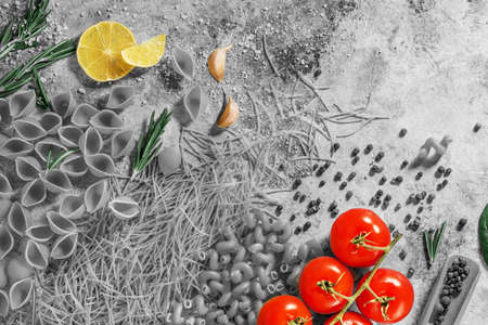 pasta, red tomatoes, garlic and herbs on a table on a dark backgroundの写真素材