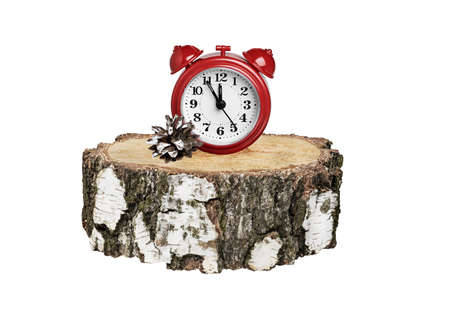 red alarm clock on a round birch timber on a white background