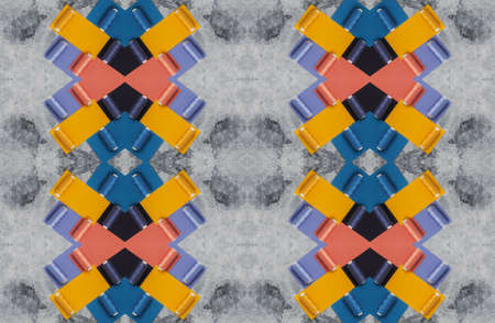 A pattern of multi-colored threads on bobbins and samples of colored fabrics against a background of gray concrete.の写真素材