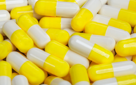Pile of medical pills in yellow capsules.