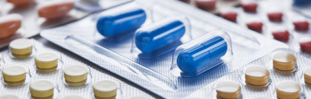 Heap of medical pills in white, blue and other colors. Pills in plastic package. Concept of...