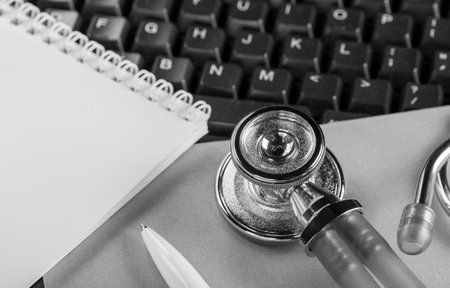 medical stethoscope on computer keyboard and ballpoint pen for notesの写真素材