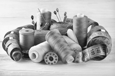 Black and white sewing kit. threads on bobbins, centimeter tape and thimble.
