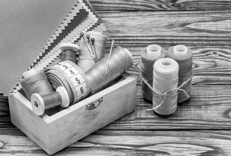sewing threads on spools in a wooden box black and white backgroundの写真素材