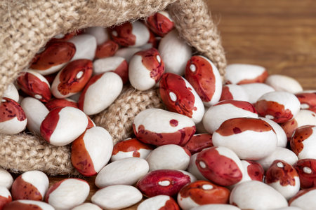 white beans with red spots in bags on a wooden table